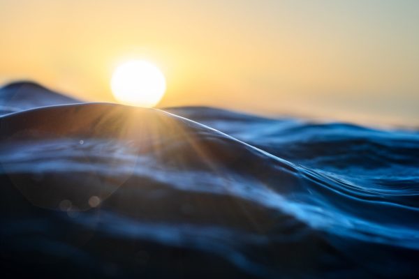Sun setting over ocean waves with a warm glow
