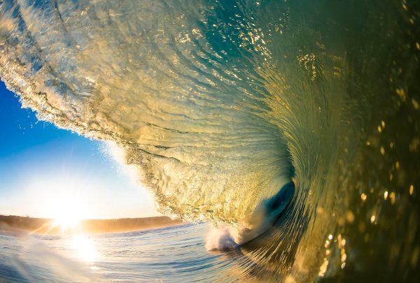 A vibrant print of a powerful ocean wave with a beautiful sunset in the background, showcasing a dynamic and colorful representation of the natural environment.