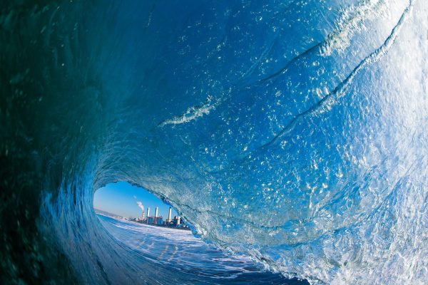 Surfing inside a tube with a cityscape visible through the wave