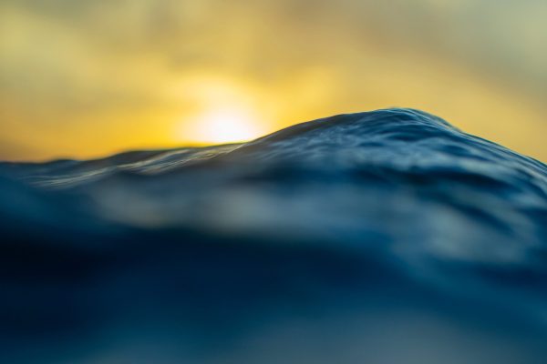 This stunning fine art photograph captures the vastness of the ocean as it ripples in shades of midnight blue, forming massive waves that evoke the ocean’s immense power.
